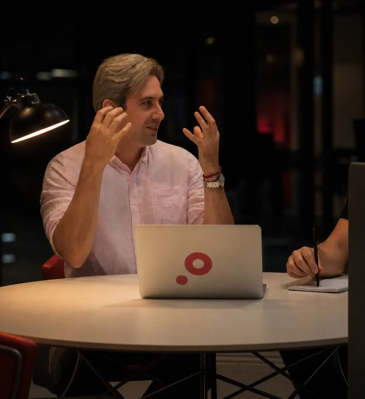 A partner talks through a project at a laptop with the Core dna logo, in a dim office.