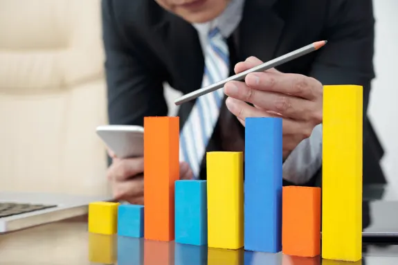 Businessman analyzing colorful bar graph on office desk.