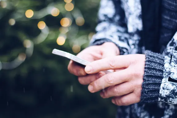 Close-up of a person holding a smartphone with a bokeh background.