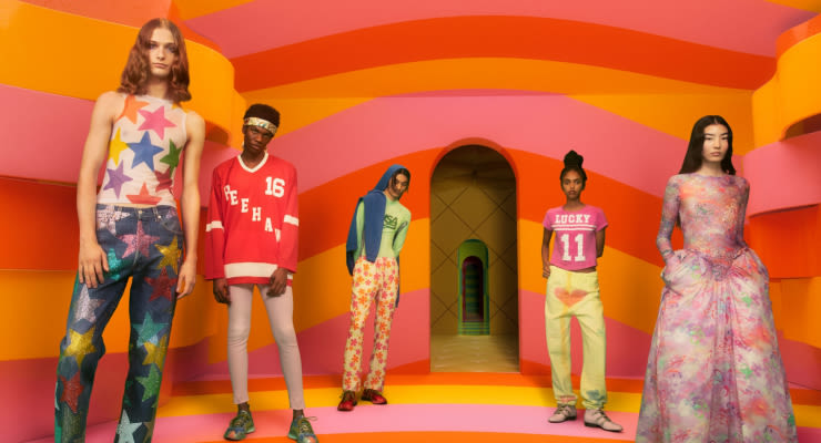 Group of models in colorful fashion against a vibrant striped background.