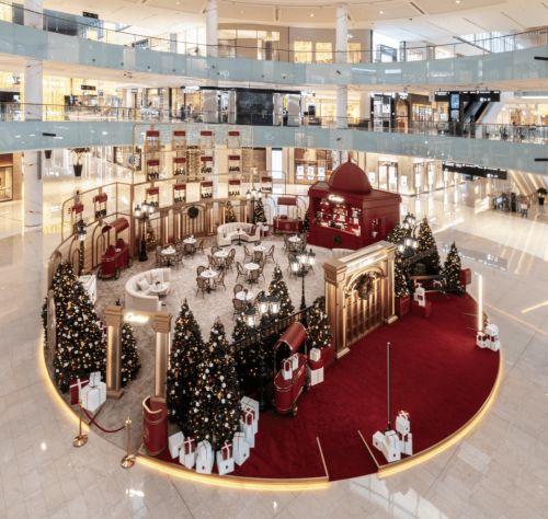 Luxury mall atrium with Christmas decor, cafe, and festive trees.