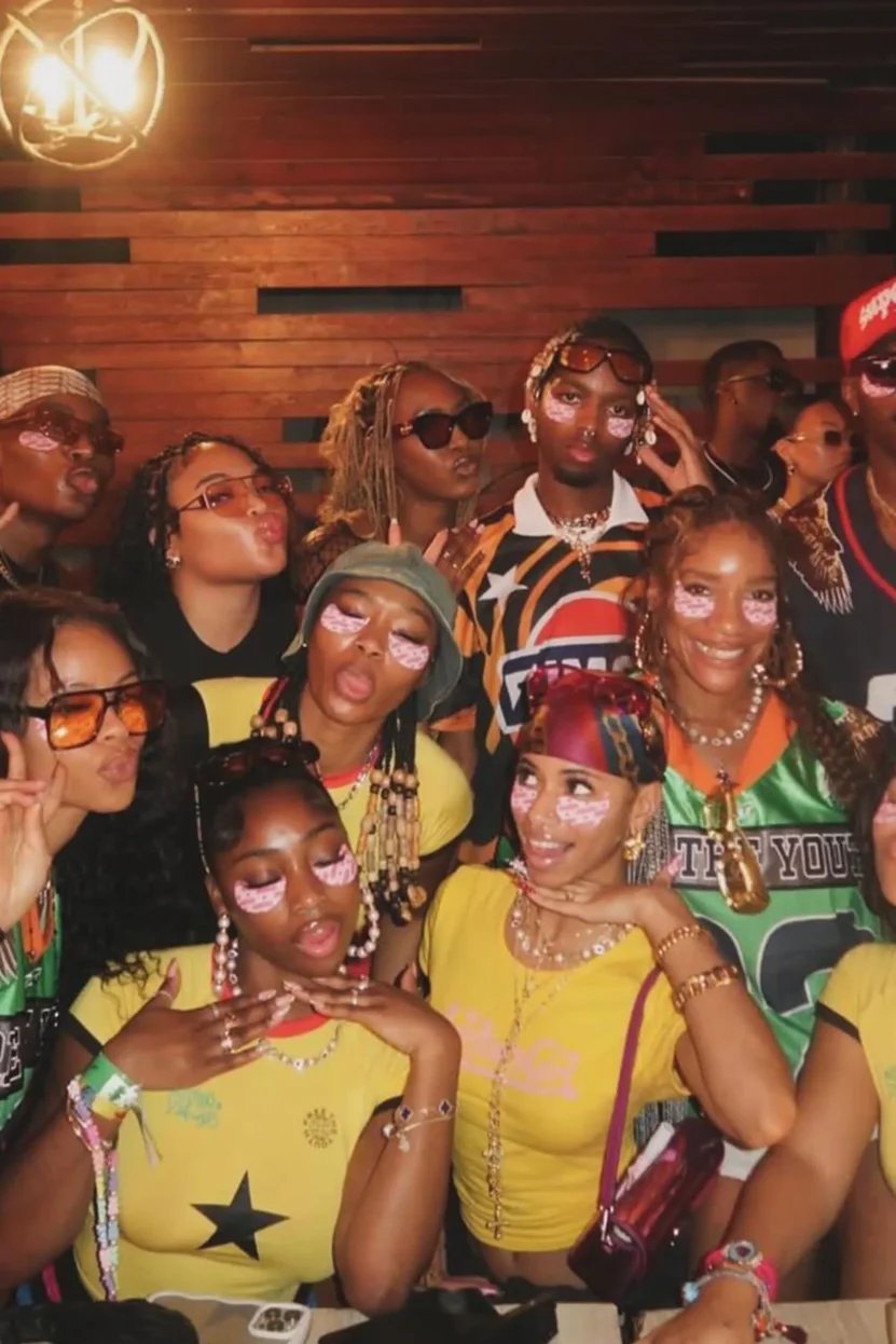 Group of people at a party with vibrant outfits and face paint, posing for a photo.
