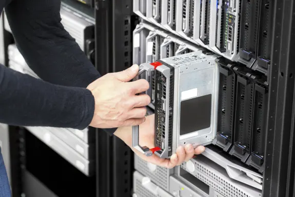 Technician installing a hard drive into a server rack in a data center.