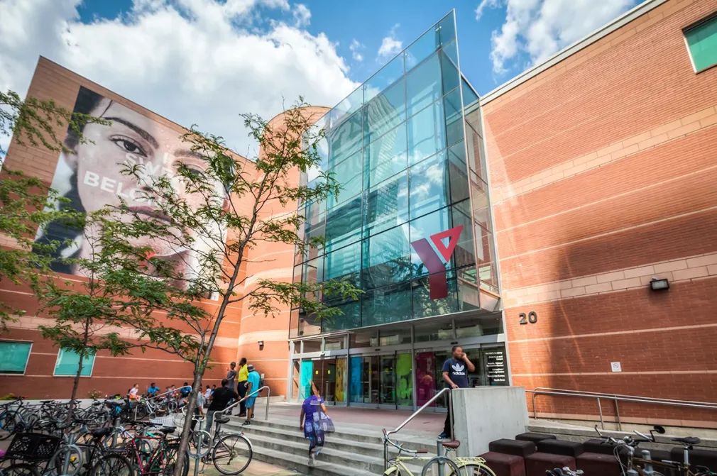 Exterior view of a YMCA building with bicycles and people outside.