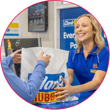 Customer service representative handing a shopping bag to a customer at a desk.
