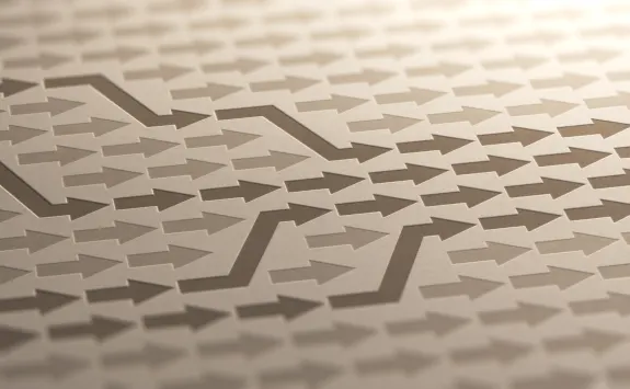 Zigzag pattern of arrows in a 3D embossed style on a beige surface.