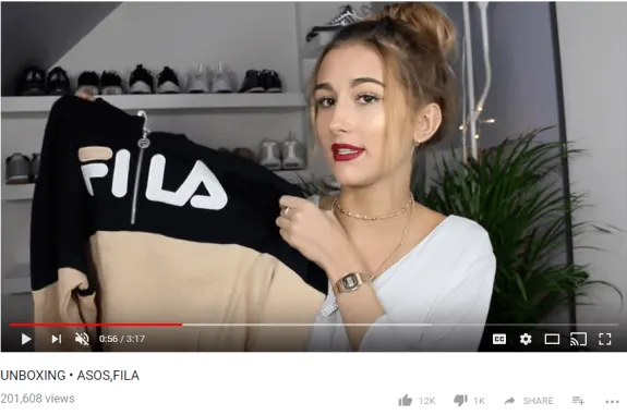 Woman holding a Fila jacket during an unboxing video