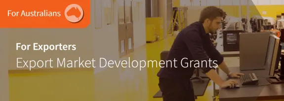 Man working on computer in industrial setting with export grants text overlay