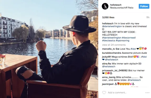 Man in black hat sitting at riverside cafe with scenic view.