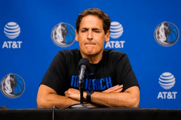 Person speaking at a press conference with a blue background.