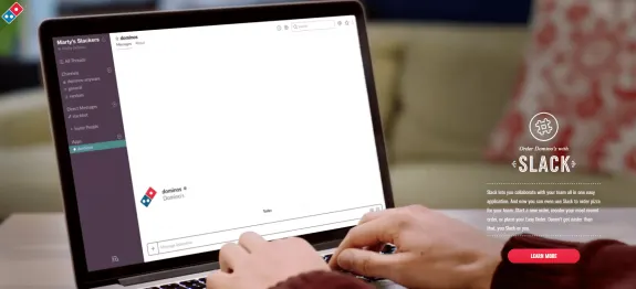 Person using Slack on a laptop to order Domino's pizza.