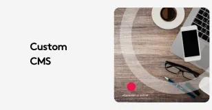 Workspace with laptop, coffee, phone, and text 'Custom CMS' on wood desk.