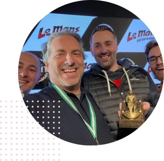 Group of men celebrating with an award on stage at Le Mans event