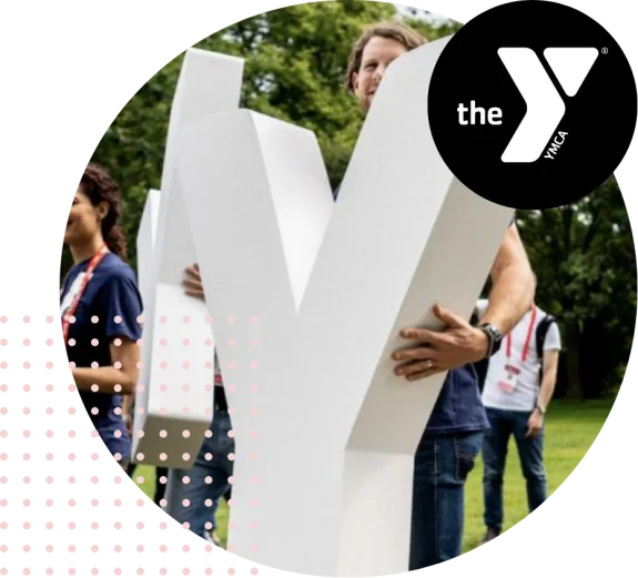 People holding large YMCA letters outdoors at an event.