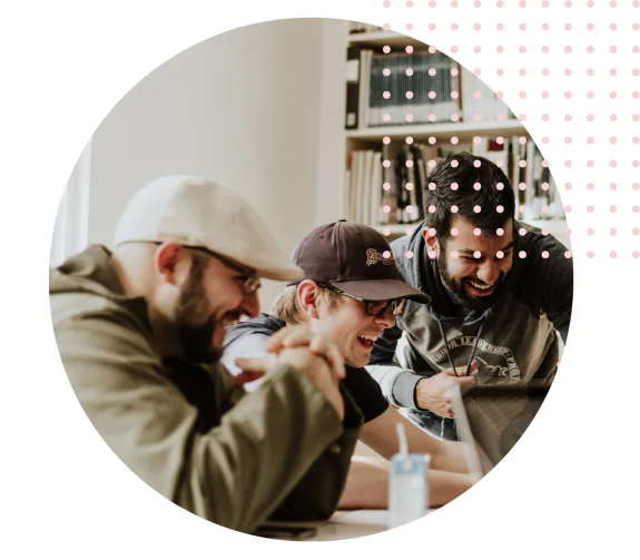Group of friends laughing together at a desk with a laptop