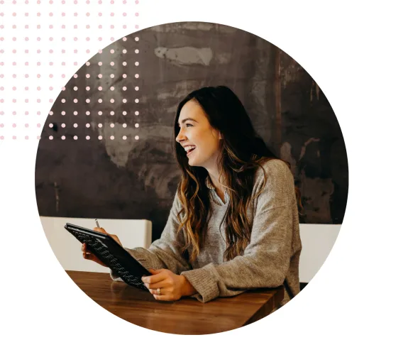 Woman smiling and holding a tablet in a cafe setting.
