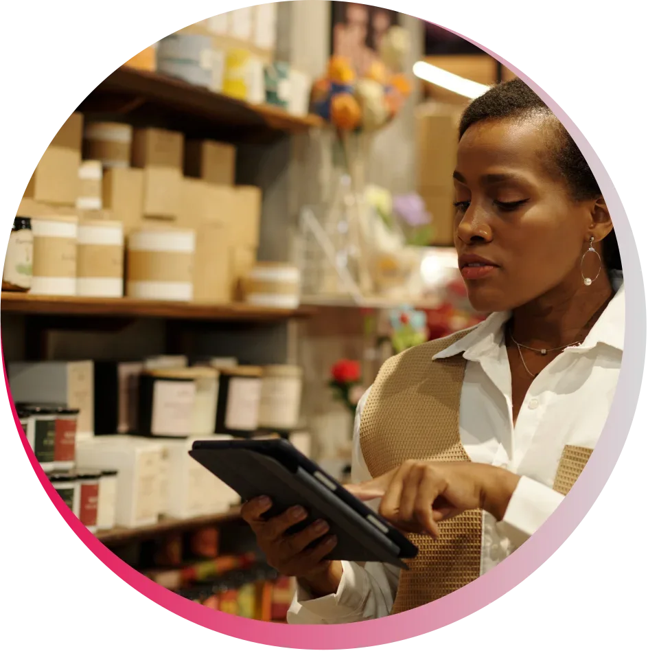 Woman using a tablet in a store aisle with products on shelves.