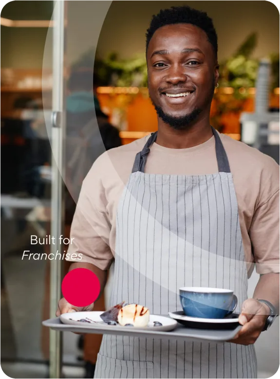 Smiling barista holding a tray with coffee and dessert in a cafe.