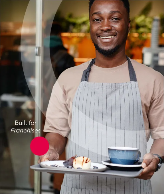 Smiling barista in apron serving coffee and dessert on a tray.